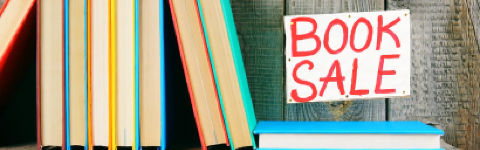 Books on a shelf with a "Book Sale" sign.