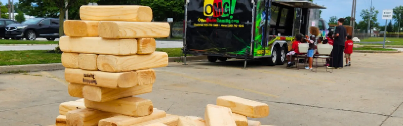 Large wooden stacking puzzle with video gaming truck in the background