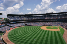 A baseball stadium with the grass freshly mowed which makes the grass look like it has lines of different shades of green
