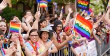 Huge group of people with face paint and rainbow flags, one of which says Peace