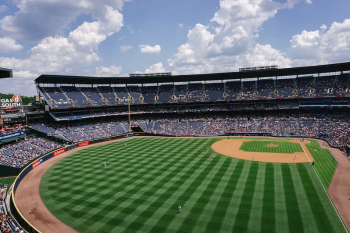 A baseball stadium with the grass freshly mowed which makes the grass look like it has lines of different shades of green