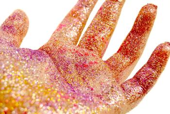 Colorful pink glitter coats someone's hand. It is shiny, bright, and sparkly.