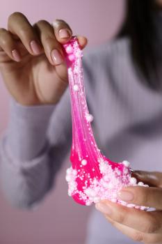 A person holding pink, glittery slime