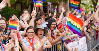 Huge group of people with face paint and rainbow flags, one of which says Peace