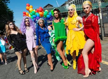 Group of drag queens in rainbow colored dresses
