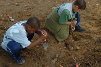 Two children dig in the dirt